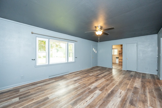 interior space featuring ceiling fan, a baseboard heating unit, a textured ceiling, and wood-type flooring