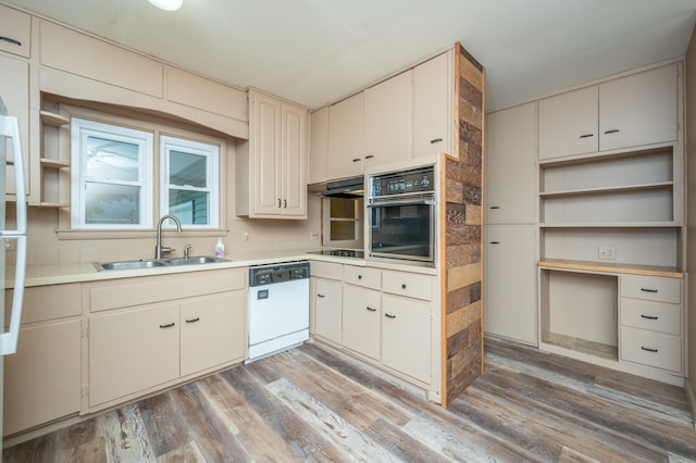 kitchen with sink, light hardwood / wood-style flooring, dishwasher, black oven, and stainless steel stovetop