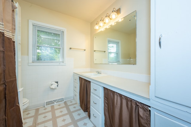 bathroom featuring vanity, tile walls, and toilet