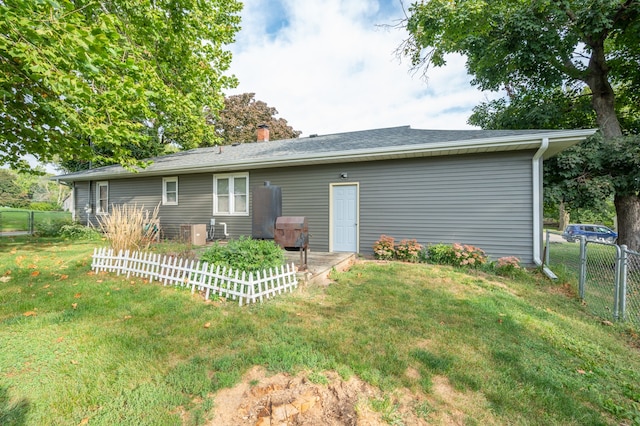 back of property with a lawn and central AC