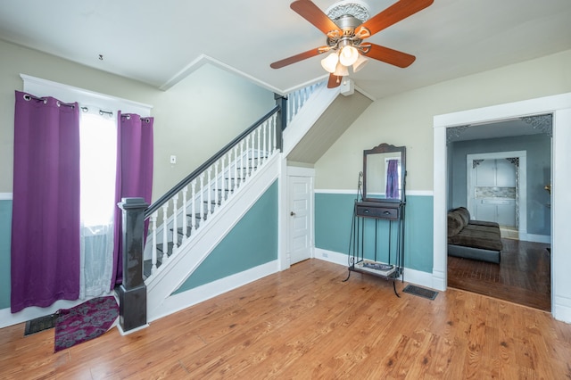 stairs featuring ceiling fan and hardwood / wood-style flooring