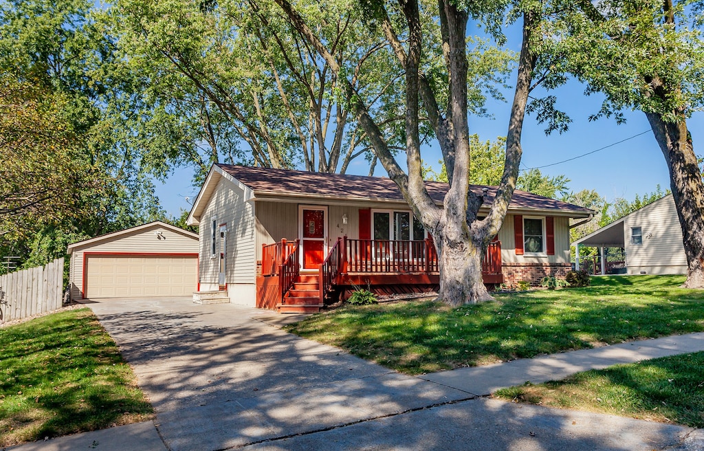 ranch-style home featuring a front yard, an outdoor structure, a detached garage, and fence