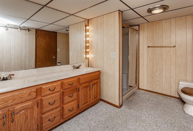 bathroom featuring vanity, a shower with shower door, wood walls, and a drop ceiling