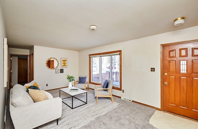 living room featuring baseboards, visible vents, a textured ceiling, and light colored carpet