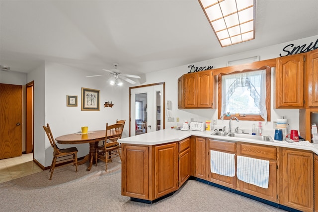 kitchen with light carpet, kitchen peninsula, ceiling fan, and sink