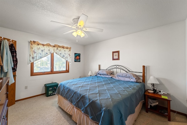 bedroom featuring a textured ceiling, ceiling fan, and light colored carpet