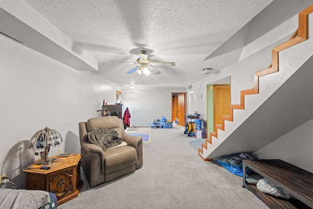 sitting room with ceiling fan, a textured ceiling, and carpet