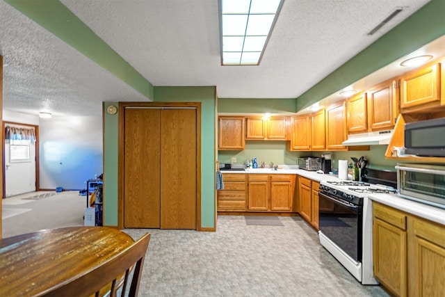 kitchen featuring white range with gas stovetop, a textured ceiling, sink, and light carpet