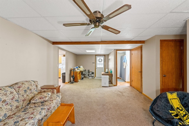 carpeted living room featuring ceiling fan and a drop ceiling