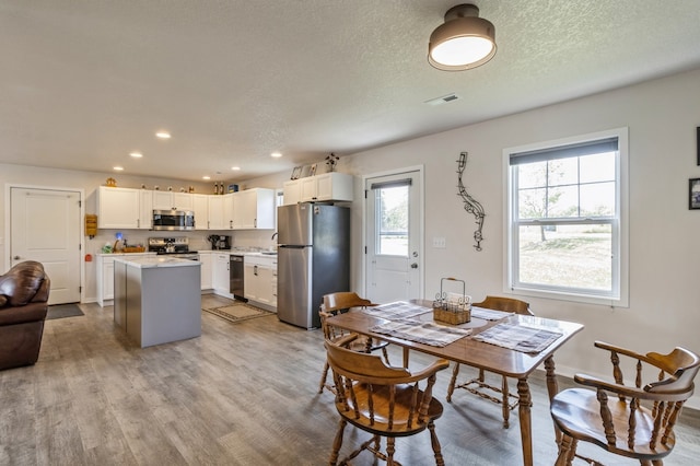 dining room featuring light wood-type flooring, a textured ceiling, and sink