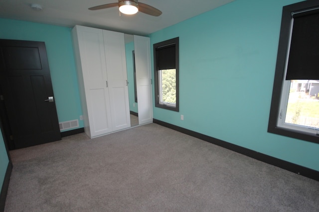 unfurnished bedroom with light carpet, a closet, and ceiling fan