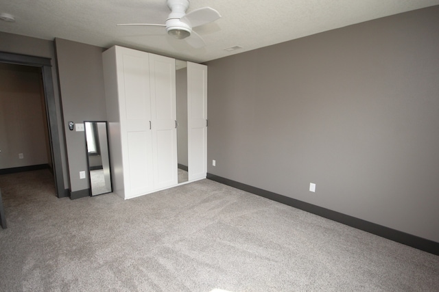 unfurnished bedroom with ceiling fan, light colored carpet, a textured ceiling, and a closet