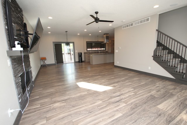 unfurnished living room featuring light hardwood / wood-style floors, a large fireplace, and ceiling fan