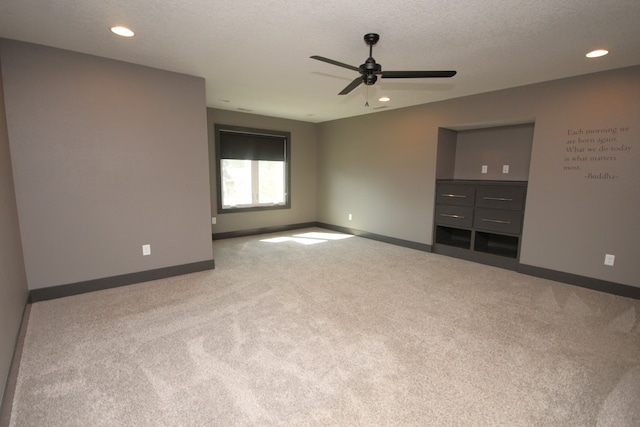 carpeted spare room featuring a textured ceiling and ceiling fan