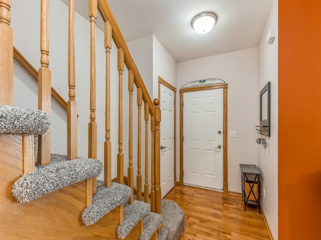 foyer entrance featuring a textured ceiling and light hardwood / wood-style floors