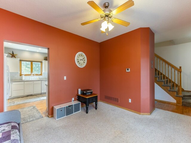 interior space featuring light carpet, ceiling fan, and sink