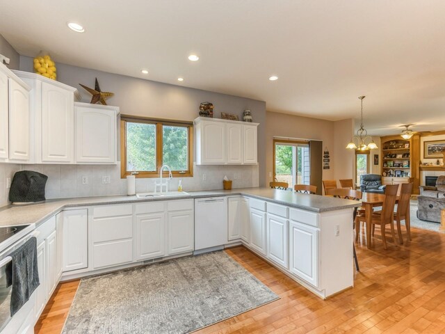 kitchen with hanging light fixtures, kitchen peninsula, white cabinetry, and white dishwasher