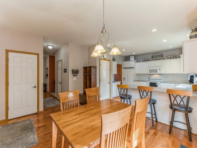 dining room with light hardwood / wood-style flooring, an inviting chandelier, and sink