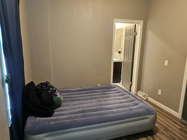 bedroom with dark hardwood / wood-style floors and ensuite bathroom