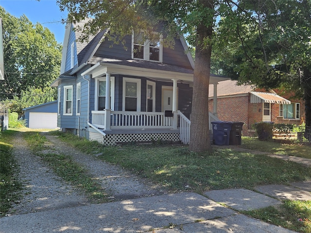 bungalow featuring an outbuilding, a porch, a garage, and a front lawn