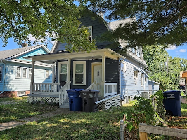 bungalow-style house featuring a front lawn, covered porch, and central air condition unit