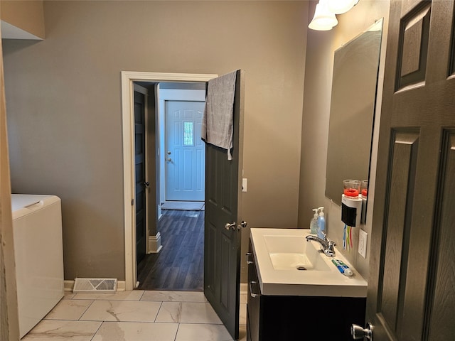 bathroom featuring washer / clothes dryer, hardwood / wood-style floors, vanity, and toilet