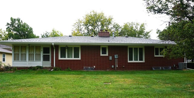 back of property featuring a lawn and central AC