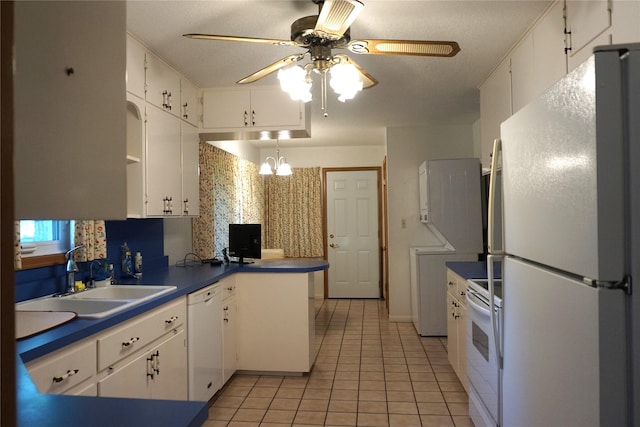 kitchen with light tile patterned floors, a peninsula, white cabinets, white appliances, and a sink