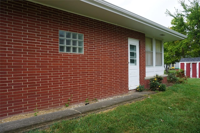 view of side of property featuring a storage shed, a lawn, brick siding, and an outdoor structure