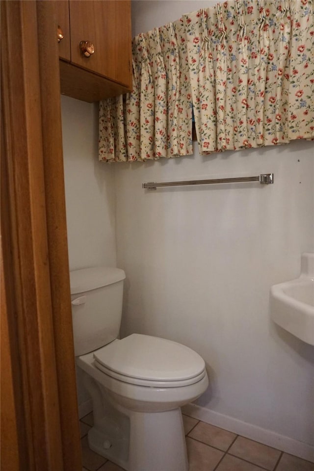 half bathroom featuring tile patterned flooring, toilet, and baseboards