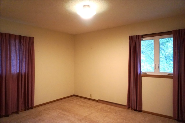 unfurnished room with baseboards and light carpet