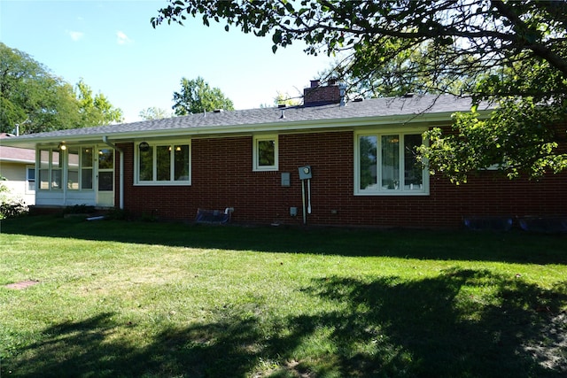 rear view of house with a lawn, brick siding, and a chimney