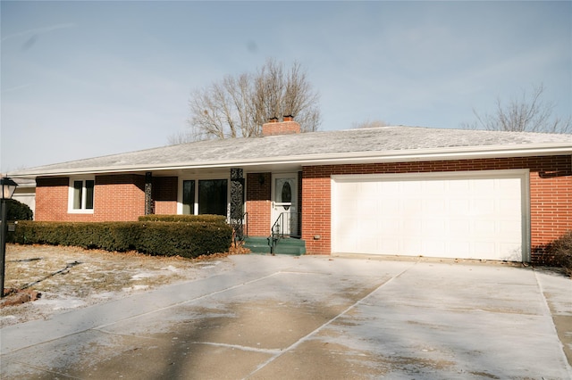 ranch-style house featuring brick siding, a shingled roof, concrete driveway, a chimney, and an attached garage