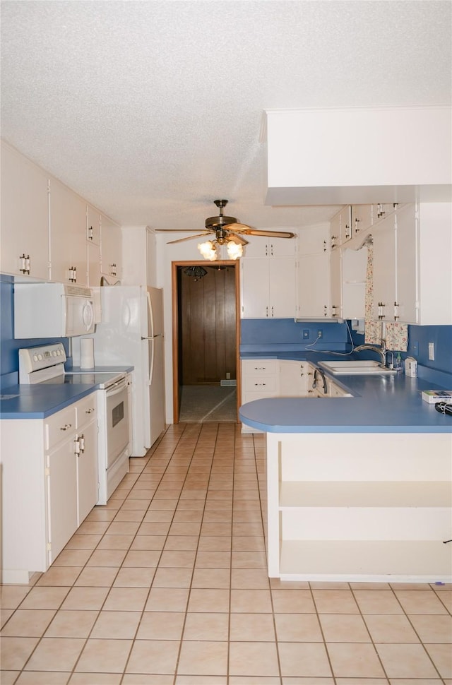 kitchen with light tile patterned floors, a peninsula, white appliances, white cabinetry, and a sink