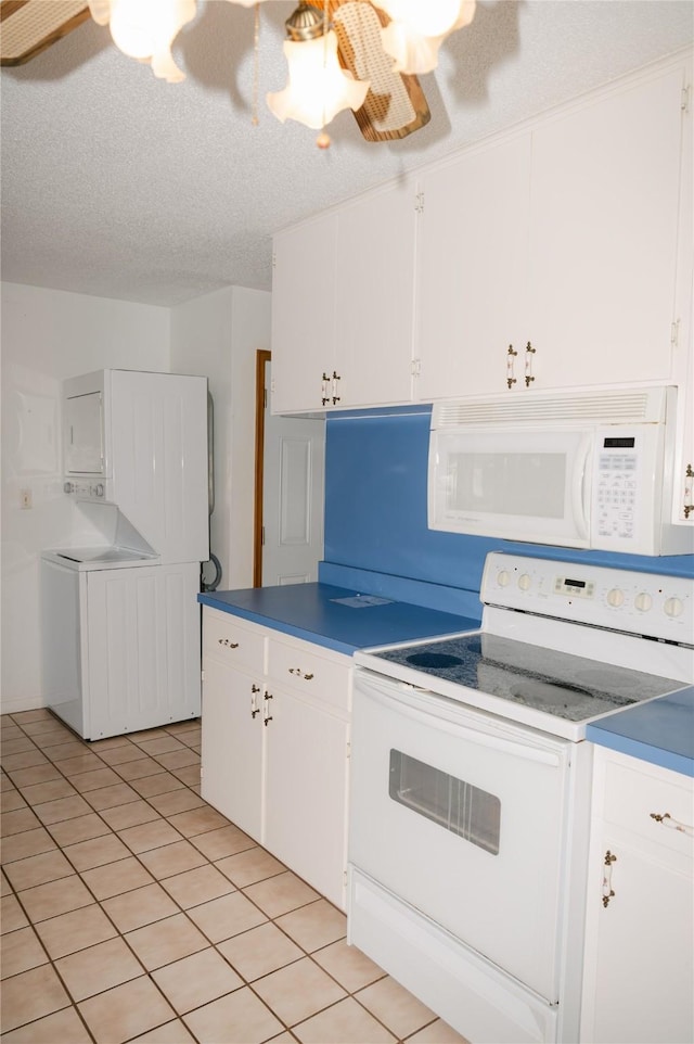 kitchen with stacked washing maching and dryer, light tile patterned flooring, white cabinets, white appliances, and a textured ceiling