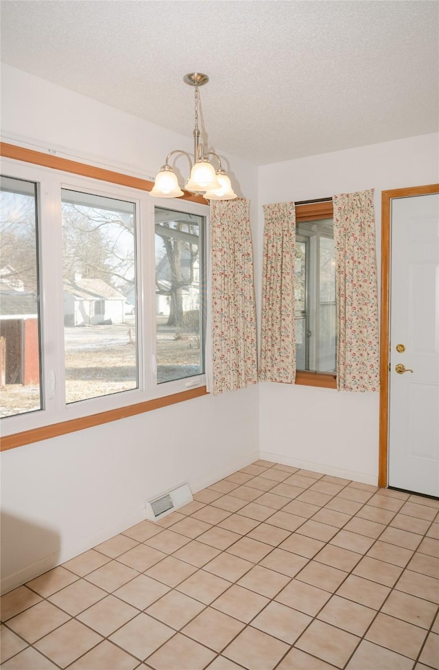 unfurnished room with a wealth of natural light, visible vents, and a textured ceiling