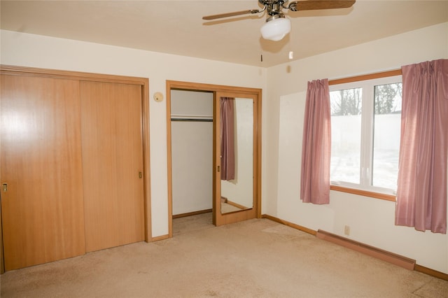 unfurnished bedroom featuring a baseboard heating unit, carpet, baseboards, and two closets