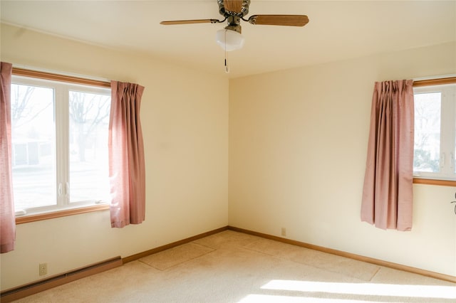 empty room featuring a wealth of natural light, light colored carpet, baseboards, and a baseboard radiator