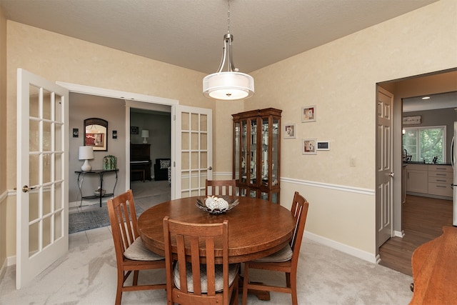 dining space featuring french doors, a textured ceiling, and light hardwood / wood-style flooring