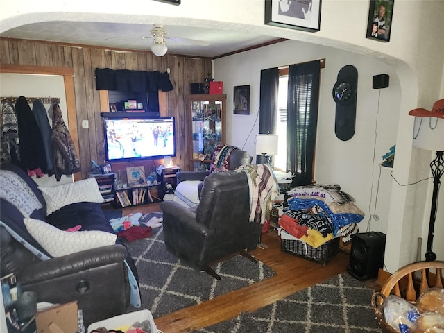 living area with wood finished floors, wood walls, and a ceiling fan