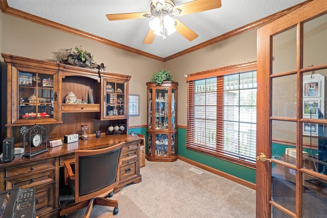 home office featuring built in desk, a textured ceiling, carpet floors, ornamental molding, and ceiling fan