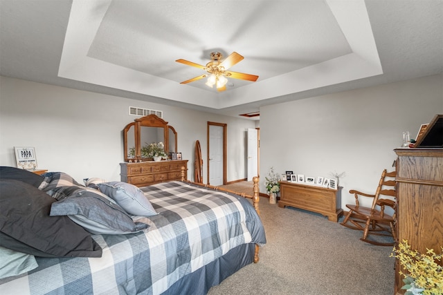 bedroom featuring a raised ceiling, carpet, and ceiling fan