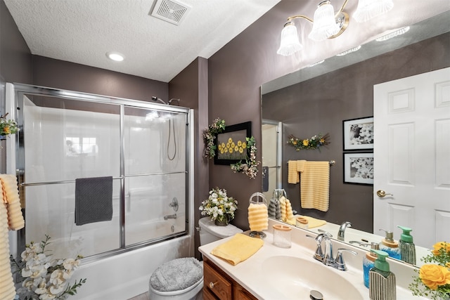 full bathroom featuring vanity, combined bath / shower with glass door, toilet, and a textured ceiling