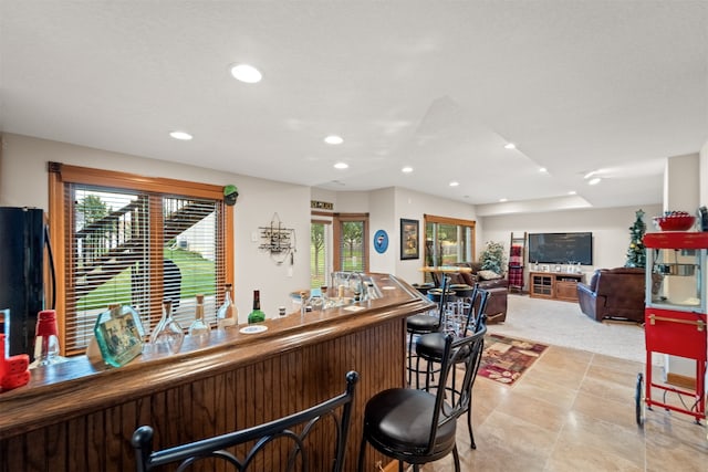 bar featuring a wealth of natural light, light colored carpet, and black refrigerator