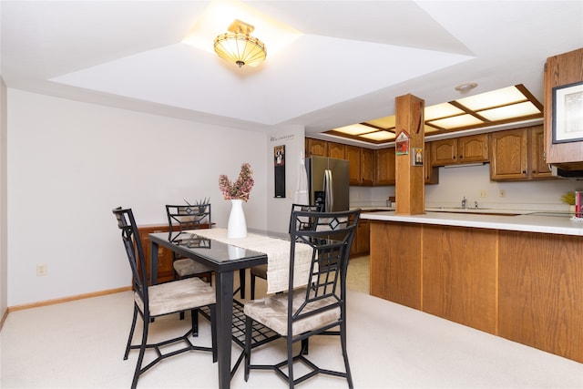 dining space with light carpet and a raised ceiling