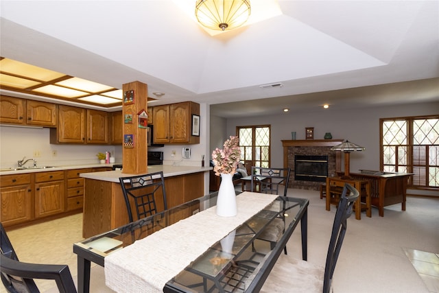 kitchen with a tray ceiling, a kitchen bar, a fireplace, and sink