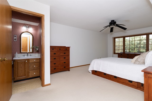 bedroom featuring light carpet, connected bathroom, ceiling fan, and sink