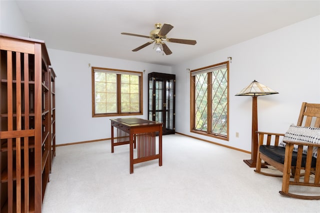 office space with a healthy amount of sunlight, ceiling fan, and light colored carpet