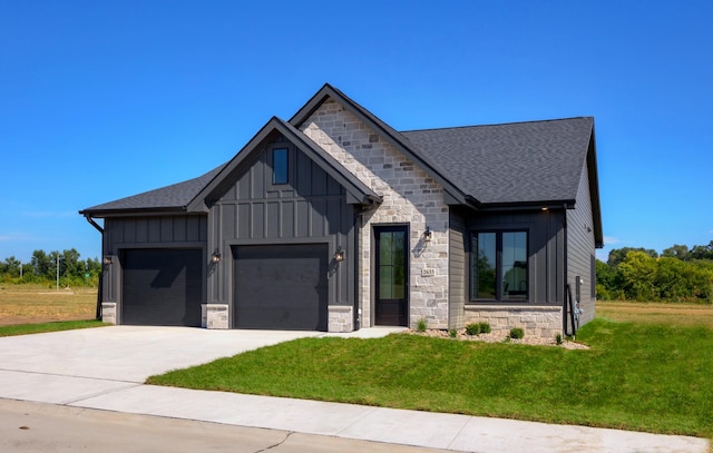view of front of home with board and batten siding, a front yard, a garage, concrete driveway, and stone siding