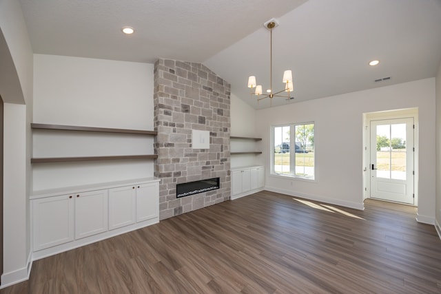 unfurnished living room with dark wood-type flooring, lofted ceiling, a fireplace, and an inviting chandelier